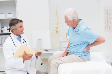 Arzt spricht mit einem Patienten, der auf einer Liege sitzt.