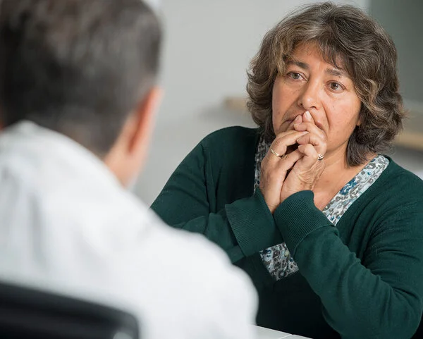 Arzt spricht mit Patientin, Foto: Tobias Schwerdt © Krebsinformationsdienst, DKFZ Patientin hält ihre Hände vor den Mund, während sie mit ihrem Arzt ihre Diagnose bespricht. Foto: Tobias Schwerdt