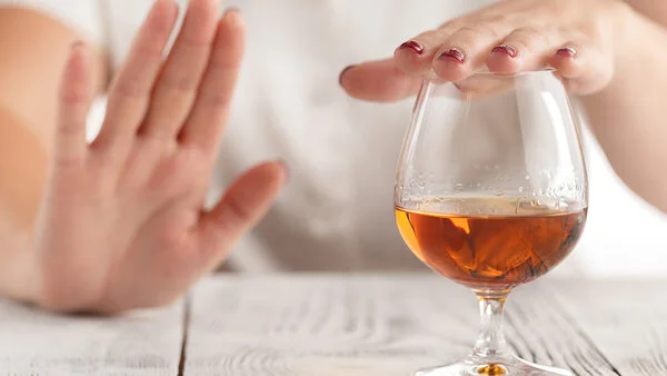Alkohol , © AndreyCherkasov, Shutterstock Ein Frau lehnt mit der Hand ein Glas Alkohol ab.