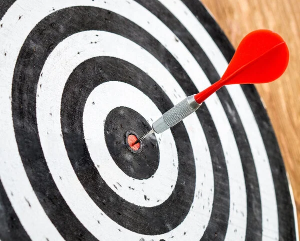 Zielscheibe, © TeroVesalainen, Pixabay (bearbeitet) Ein Dartpfeil steckt zielgenau im Bullseye einer Dartscheibe