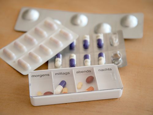 Verschiedene Tablettenblister und eine Tablettenschachtel als Dosierhilfe für die Einnahme verschiedener Tabletten zu festen Zeitpunkten am Tag.