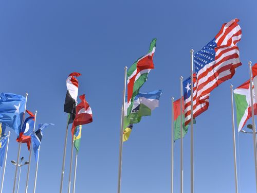 Die Flaggen verschiedene Länder an mehreren Fahnenmasten wehen im Wind.