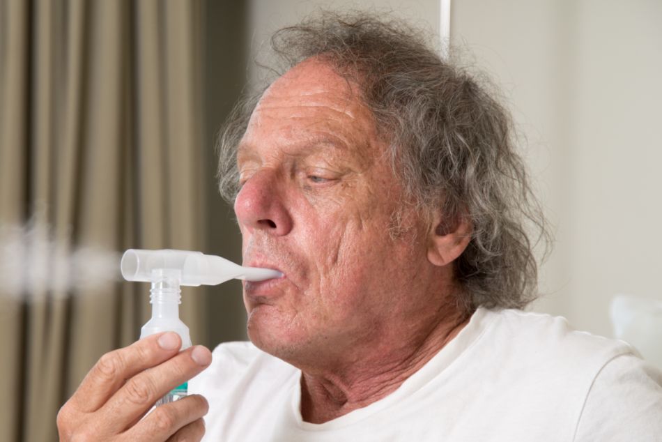 Älterer Mann macht mit einem Atemgerät einen Atemtest.