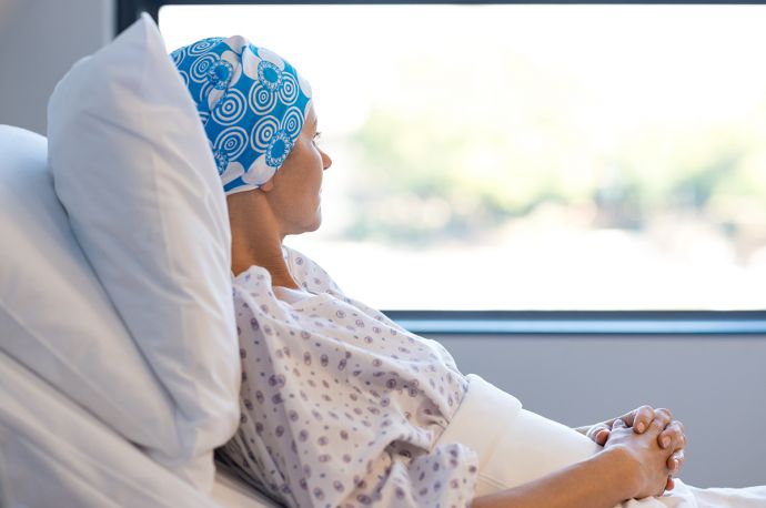 Frau mit Kopftuch in einem Krankenhausbett