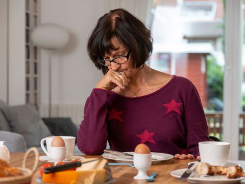Frau sitzt appetitlos vor dem Frühstück. Bild: Tobias Schwerdt © Krebsinformationsdienst, DKFZ