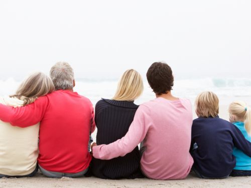 Familie aus drei Generationen sitzt am Strand