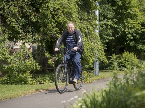 Ein Herr fährt mit dem Fahrrad auf einem Fahrradweg durch die Natur