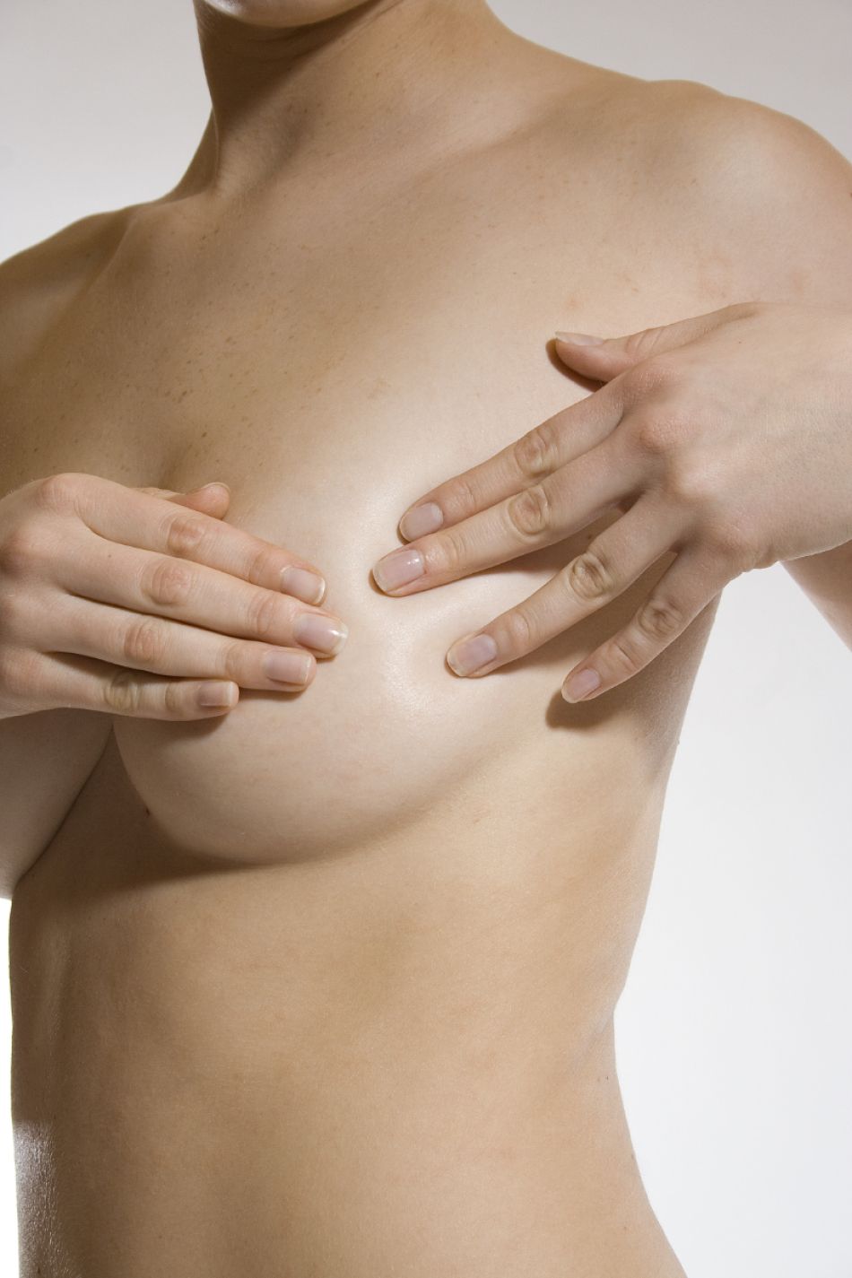 Eine Frau tastet sich die linke Brust ab.