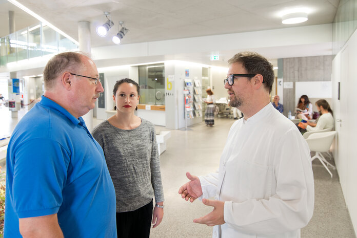 Patient, Tochter und Arzt besprechen sich in der Klinik