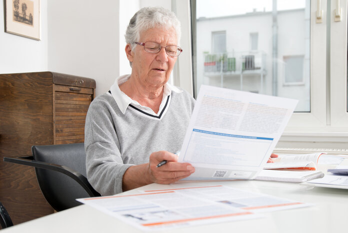 Ältere Frau liest Faltblätter