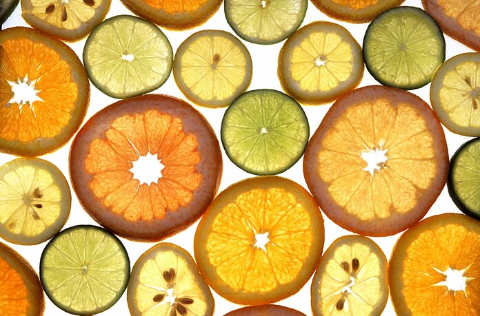 Zitrusfrüchte in Scheiben vor hellem Hintergrund (Zitronen, Limetten, Orangen)