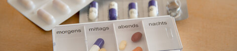 Verschiedene Tablettenblister und eine Tablettenschachtel als Dosierhilfe für die Einnahme verschiedener Tabletten zu festen Zeitpunkten am Tag.