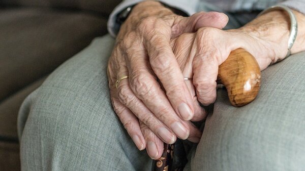 alte Hände, © Sabine van Erp, Pixabay Nahaufnahme einer Seniorin, die mit übereinander gelegten Händen auf dem Sofa sitzt.