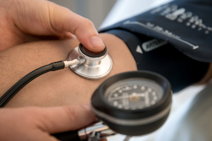 Bildausschnitt: Blutdruckmessen am Arm mit Stethoskop.