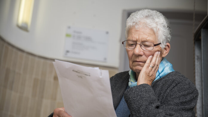 Frau liest besorgt Arztbrief im Treppenhaus