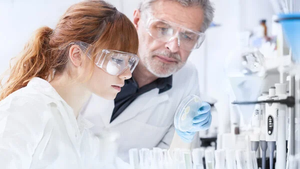 Forschung im Labor, © Matej Kastelic, Shutterstock Zwei Forscher begutachten im Labor eine Schale mit Bakterien.