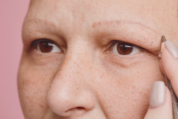 Eine Krebspatientin zeichnet sich Augenbrauen nach. Zu sehen ist ein Ausschnitt ihres Gesichts.