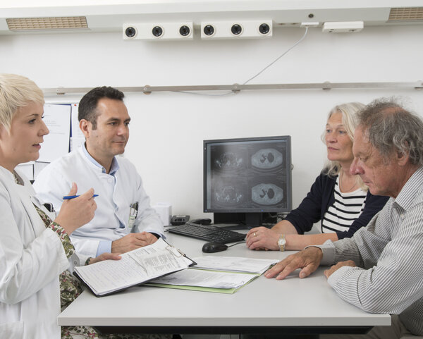 Ein Patient mit Lungenkrebs und seine Angehörige im Gespräch mit zwei Ärzten.