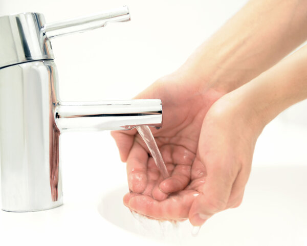 2 Hände werden unter einen fließenenden Wasserhahn gehalten.