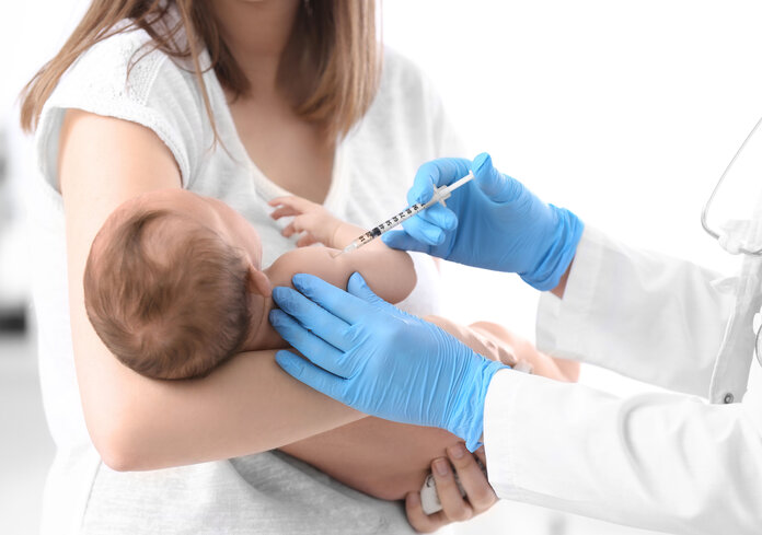 Säugling im Arm einer Frau erhält eine Spritze.