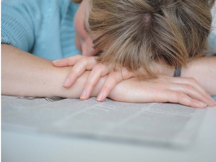 Frau liegt erschöpft auf einer Zeitung. Bild: Tobias Schwerdt © Krebsinformationsdienst, DKFZ