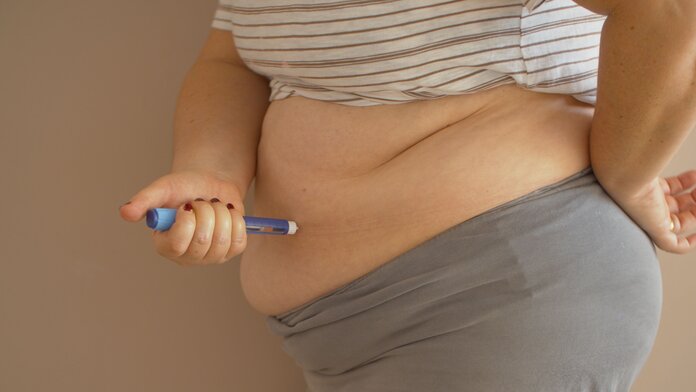 Eine übergewichtige Frau spritzt sich ein Diabetes Medikament.