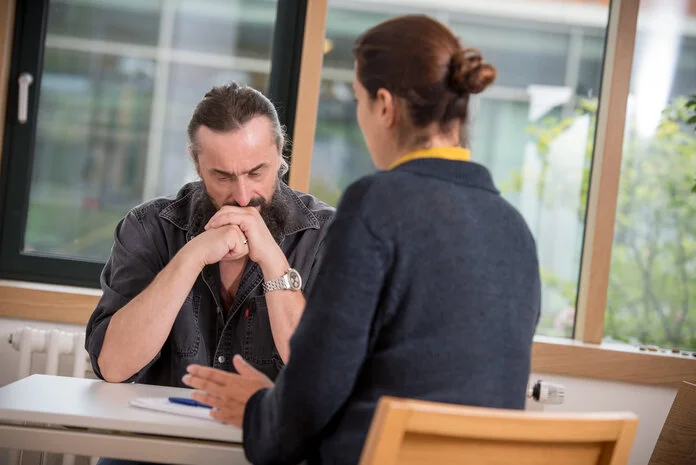 Psychoonkologische Beratung, © Krebsinformationsdienst, DKFZ; Foto: Tobias Schwerdt Mann sitzt bedrückt an einem Tisch, vor ihm sitzt eine Psychoonkologin
