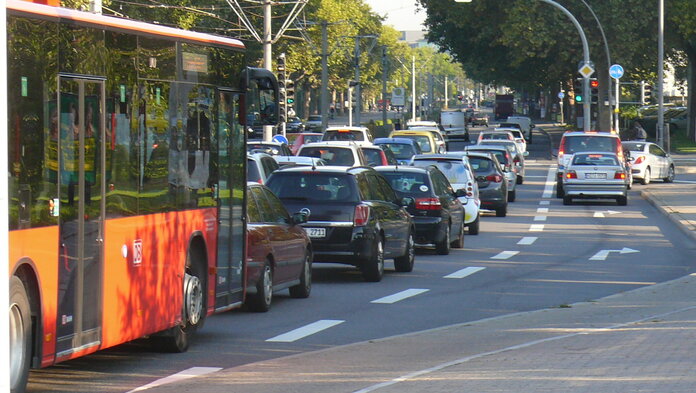 Mehrere Autos und ein Bus stehen vor einer Ampel.