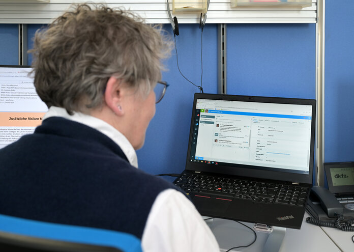 Eine Ärztin schaut auf den Bildschirm ihres Laptops, auf dem ein Chat zu sehen ist.