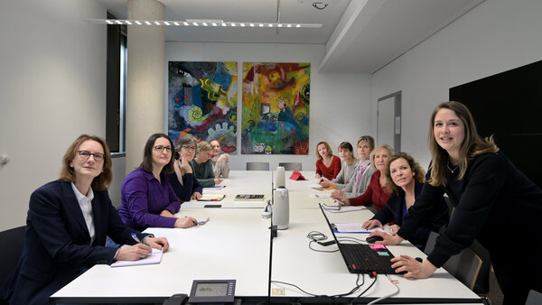 Mitarbeiterinnen des Krebsinformationsdienstes bei einer Präsentation, © Krebsinformationsdienst, DKFZ; Foto: Klaus Landry Mitarbeiterinnen des Krebsinformationsdienstes sitzen an einem Besprechungstisch und hören bei einer Präsentation einer Kollegin zu.
