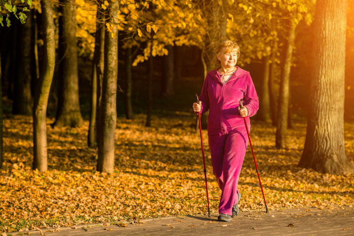 Ältere Frau walkt im Herbst mit Walking-Stöcken.