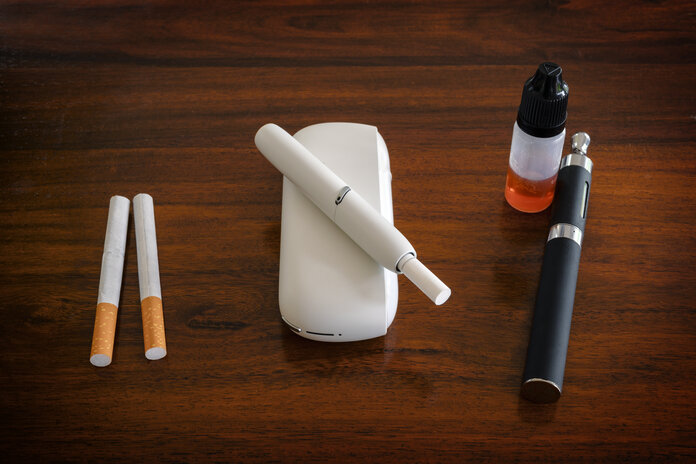 Foto von Zigaretten, einem Tabakerhitzer mit eingestecktem Tabakstick und einer E-Zigarette mit Nachfüllpack.