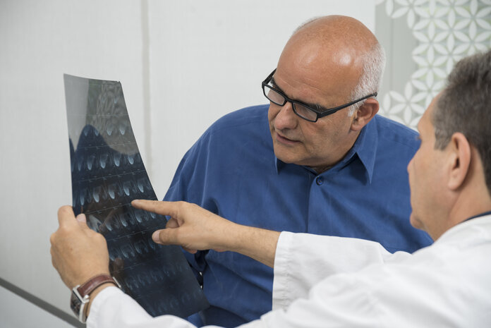 Ein Arzt erklärt einem Patienten eine Röntgenaufnahme.