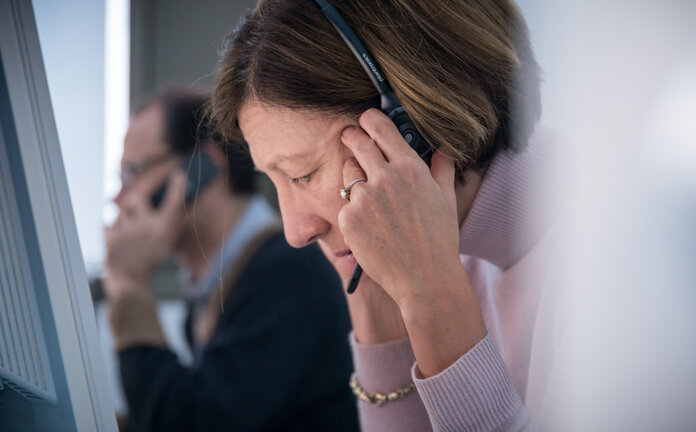 Eine Ärztin im Telefondienst des Krebsinformationsdienstes telefoniert fokussiert und hört sehr konzentriert zu.