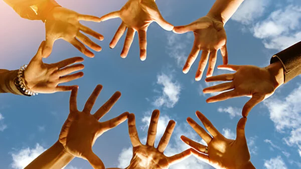 Kreis aus Händen, © cppzone/stock.adobe.com Viele gespreizte Hände die vor einem Himmel einen geschlossenen Kreis bilden.