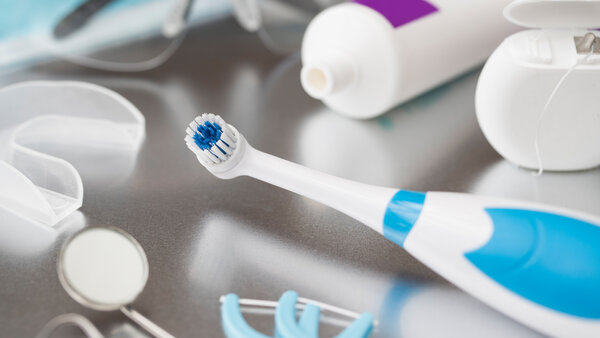 Verschiedene Utensilien für die Zahnpflege bei Krebs liegen auf einem Tisch: elektrische Zahnbürste, Zahnpasta, Zahnseide, Spiegel etc.
