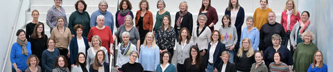 Mitarbeitende des krebsinformationsdienst stehen gruppiert zu einem Teamfoto auf einer Treppe