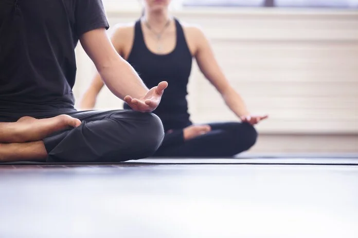Yoga, © ZephyrMedia, Shutterstock Zwei Personen sitzen im Schneidersitz