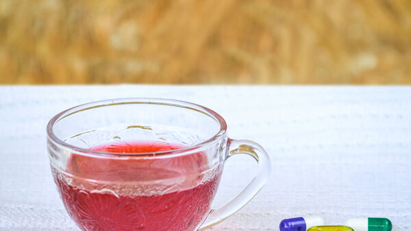 Pflanzliche Heilmittel, © AlessandraRC, Shutterstock Neben einer Tasse Tee liegen verschiedene Kapseln und Tabletten.