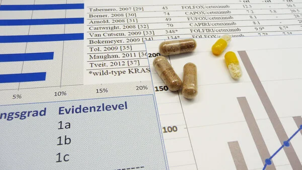 Evidenz, © Krebsinformationsdienst, DKFZ Ausdruck mit Literaturangaben wissenschaftlicher Arbeiten, unten links sind die Evidenzlevel (Beweiskraft) aufgeführt und auf dem Blatt liegen Tablettenkapseln.