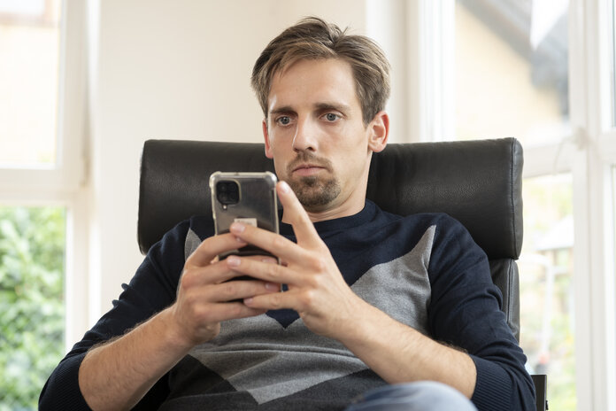 Ein Mann schaut auf den Bildschirm eines Smartphones.