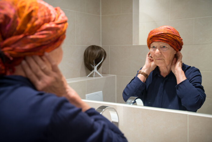 Ältere Frau mit Kopftuch vor Spiegel., © Krebsinformationsdienst, Deutsches Krebsforschungszentrum; Foto: Tobias Schwerdt Ältere Frau mit Kopftuch betrachtet sich in einem Badezimmerspiegel.