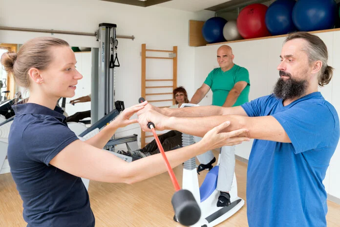 Rehasport, © Krebsinformationsdienst, DKFZ; Foto: Tobias Schwerdt Ein Mann trainiert mit einer Physiotherapeutin in einem Sportraum.