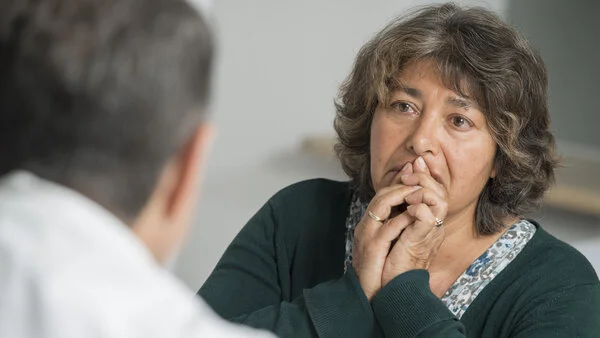 Arztgespräch, © Krebsinformationsdienst, DKFZ; Foto: Tobias Schwerdt Patientin hält ihre Hände vor den Mund, während sie mit ihrem Arzt ihre Diagnose bespricht.