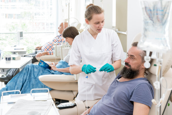 Ein Mann bekommt eine Chemotherapie, eine Krankenschwester spricht mit ihm.