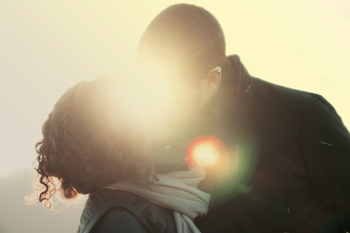 Mann und Frau küssen sich bei Gegenlicht.