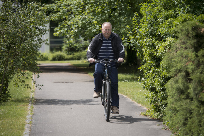 Älterer Mann fährt im Grünen Fahrrad.
