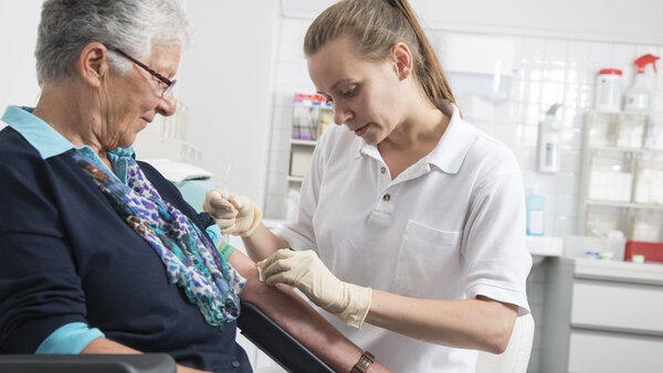 Eine Arzthelferin nimmt einer Patientin Blut ab.