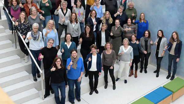 Mitarbeitende des Krebsinformationsdienstes stehen zu einem Gruppenfoto gruppiert eine Treppe aufwärst.