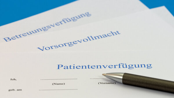 Auf einem Tisch liegen eine Patientenverfügung, eine Vorsorgevollmacht und eine Betreuungsverfügung, darauf liegt ein Stift.